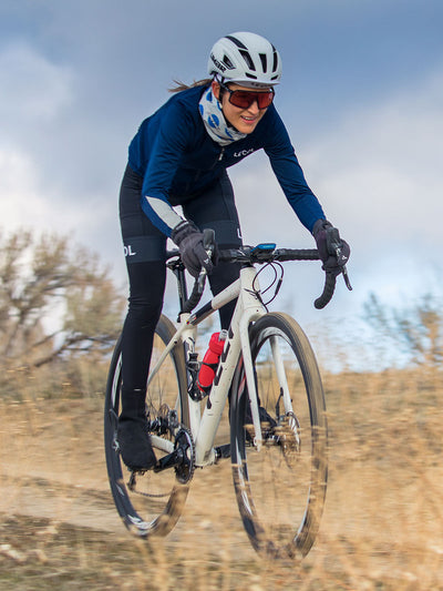 Woman riding gravel bike while wearing Limar bike helmet and sunglasses
